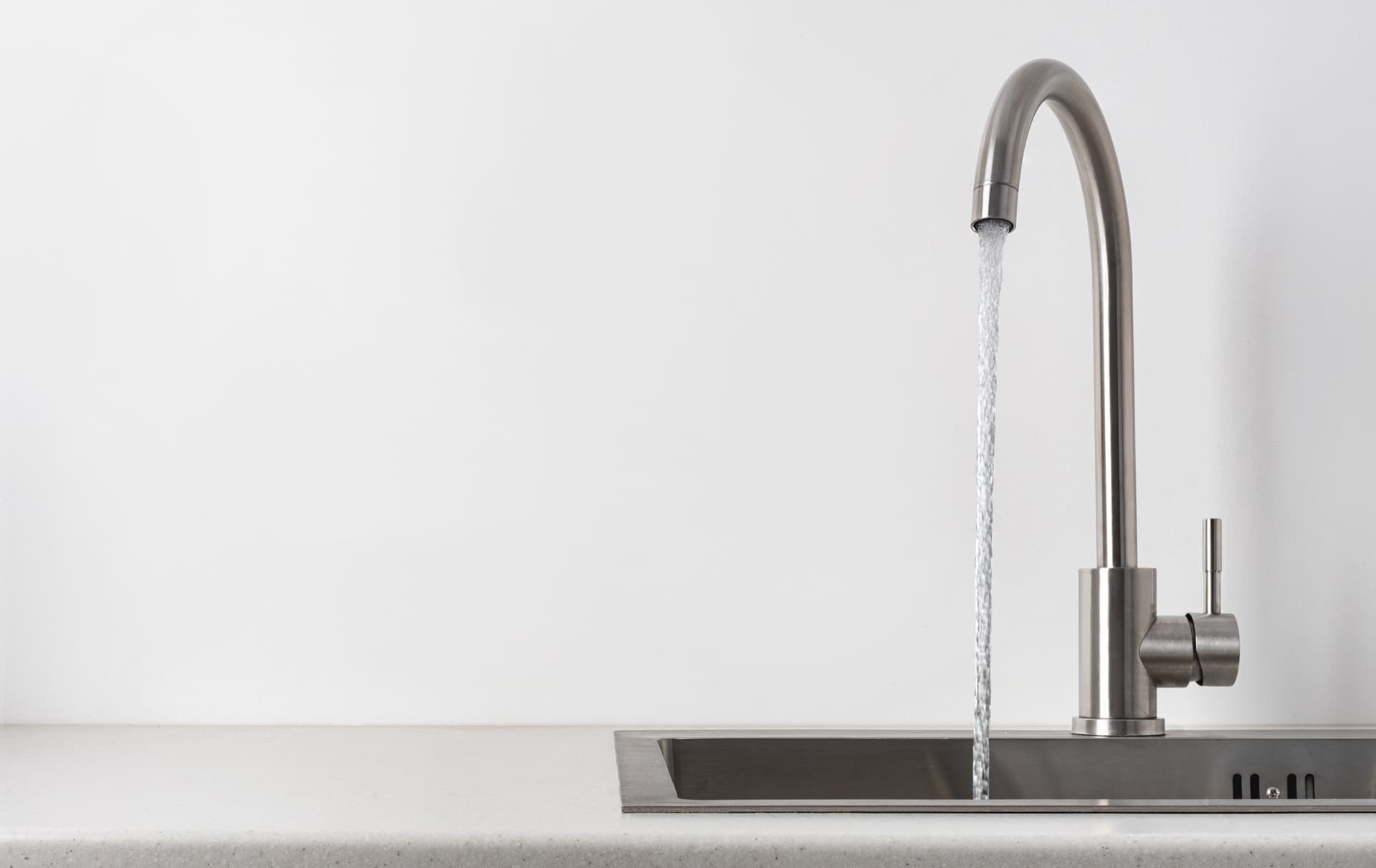 Clean filtered water running from a modern stainless steel kitchen faucet