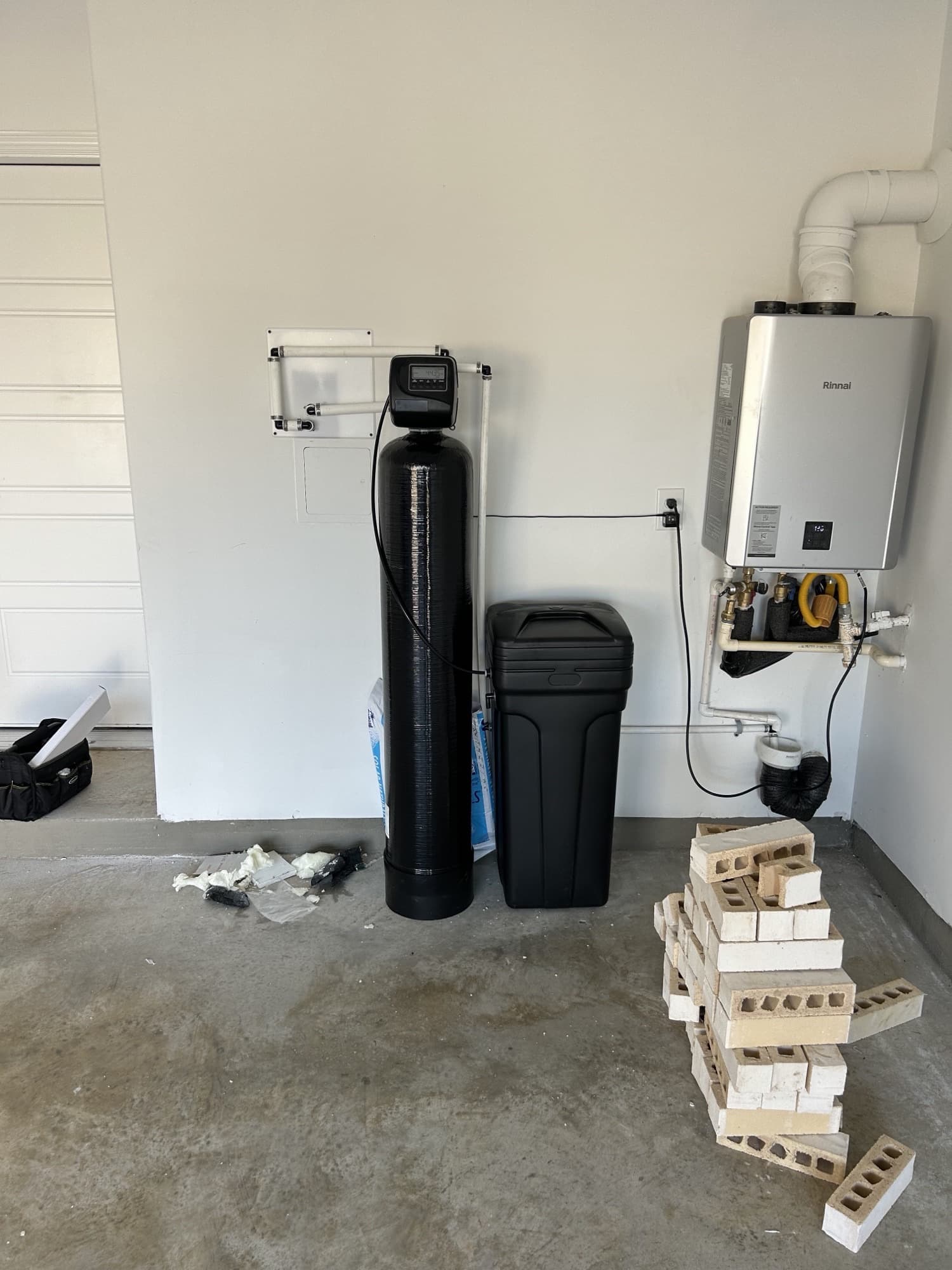 Water softener and brine tank installed next to a tankless water heater in a garage